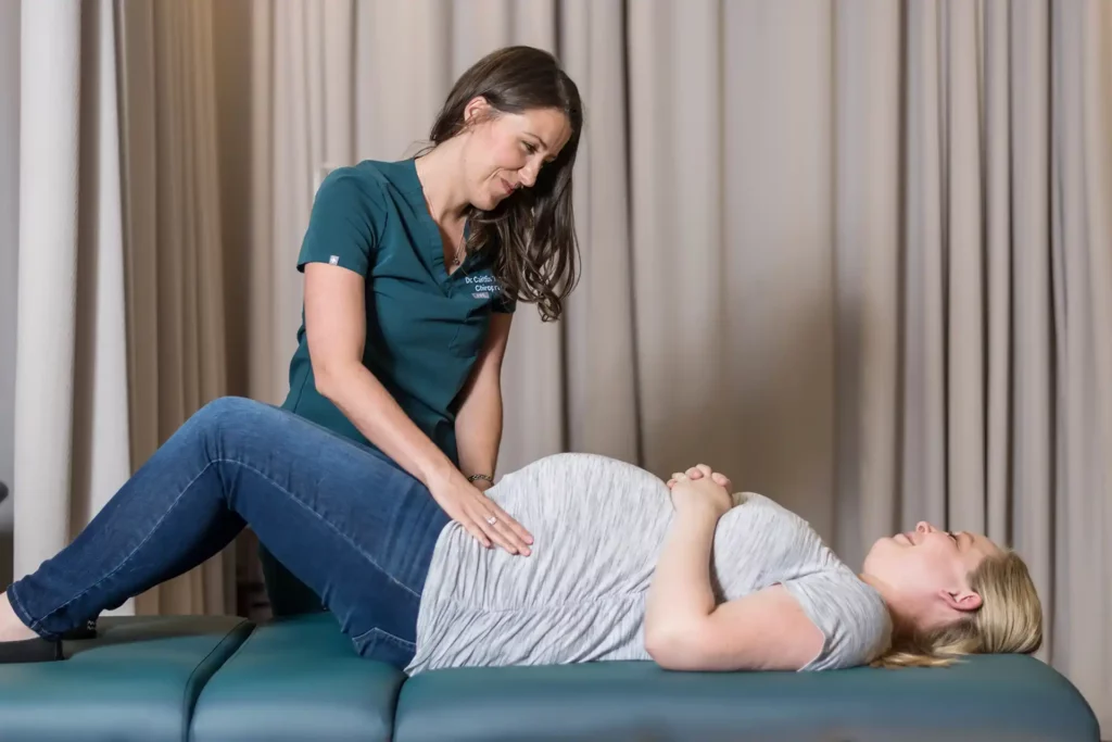Female chiropractor in the Woodlands giving pregnancy chiropractic care to a patient lying down on her back